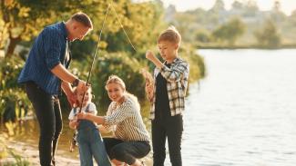 famille de quatre personnes pêchant au bord d'un lac